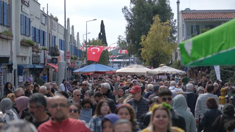 Festival alanında omuz omuza yürüyen kalabalık, arkada şemsiyeli tezgâhlar